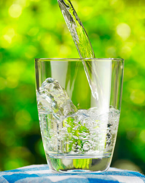 Wasser wird in Glas eingeschenkt