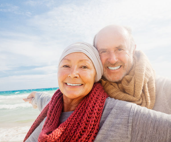Glückliches älteres Paar am Strand - trotz Inkontinenz